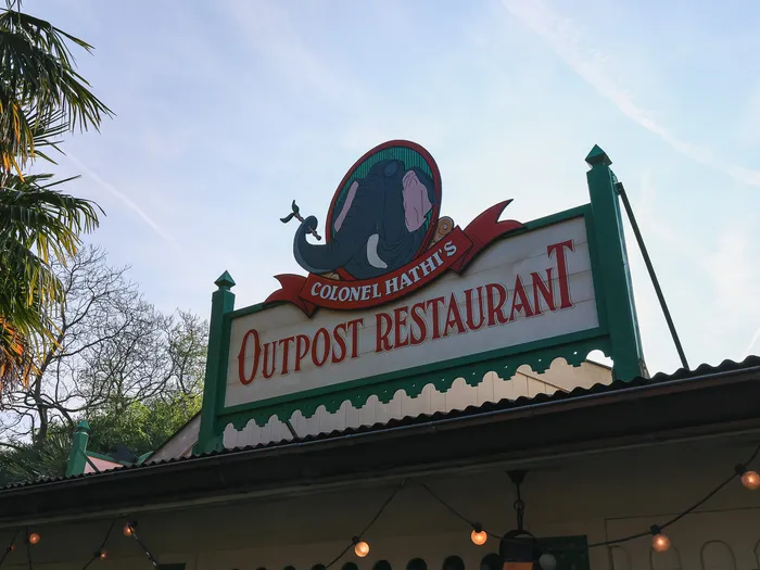 Enseigne du Colonel Hathi’s Outpost Restaurant ornée d’un éléphant, sur fond de ciel bleu à Adventureland.