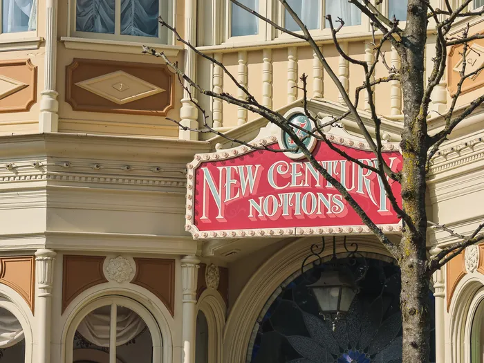 Red New Century Notions sign on the facade, bare tree branches in the foreground