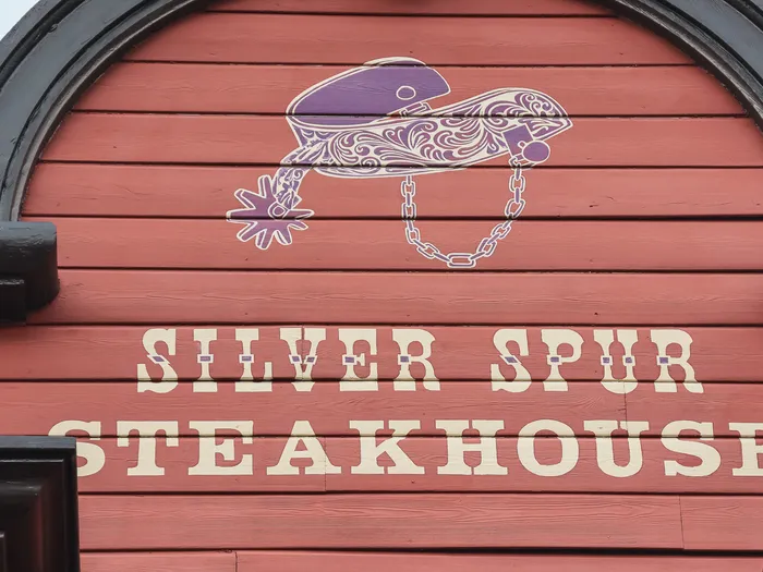 Enseigne « Silver Spur Steakhouse » peinte sur la façade rouge du restaurant de Frontierland, avec éperon stylisé.