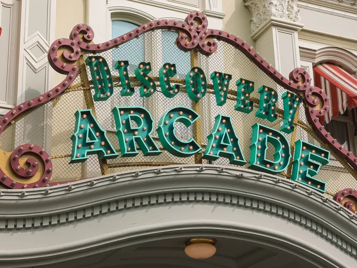 Enseigne verte et rose « Discovery Arcade » à ampoules sur une façade de Main Street