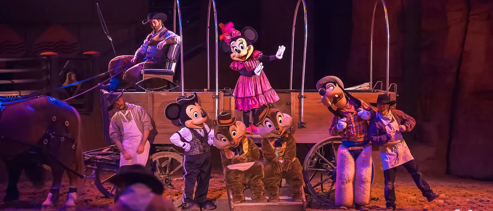 Personnages Disney costumés en cow-boys autour d’une diligence dans une arène western