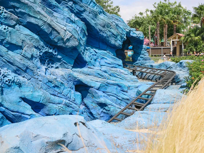 Rochers bleus stylisés et rails du parcours de montagnes russes de l’attraction Crush’s Coaster à Worlds of Pixar.