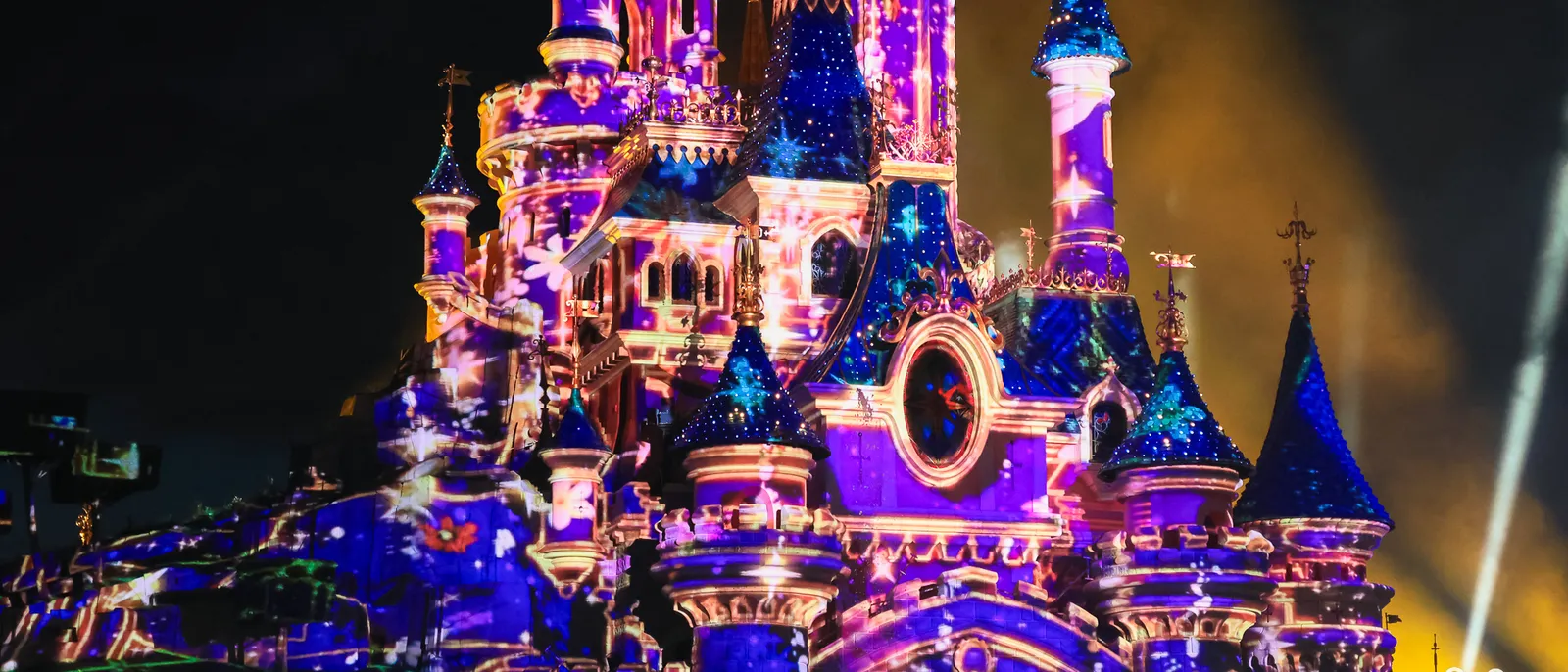 Château recouvert de projections violettes et d’étoiles scintillantes pendant un spectacle nocturne à Disneyland Paris