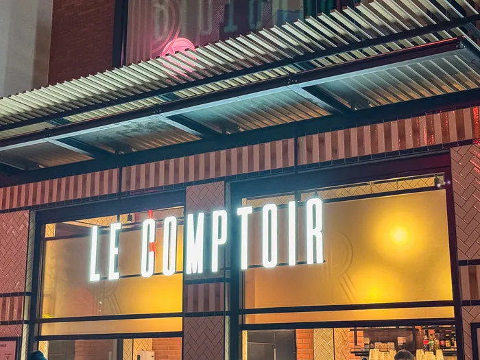 Façade du restaurant Le Comptoir à Disney Village avec son enseigne lumineuse allumée le soir.