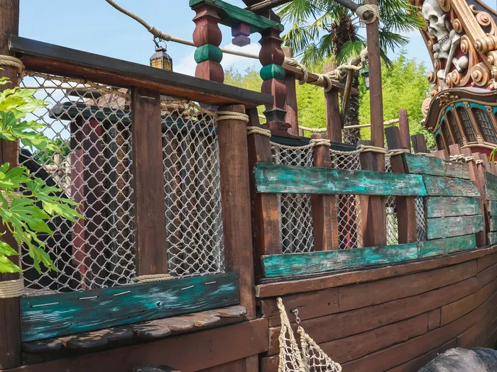 Coque de bateau pirate en bois avec planches vertes et figure de proue à la Plage des Pirates, sous un ciel bleu
