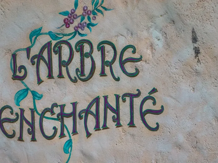 Nom « L'Arbre Enchanté » peint en lettres colorées avec fleurs et feuillage sur un mur clair à Fantasyland