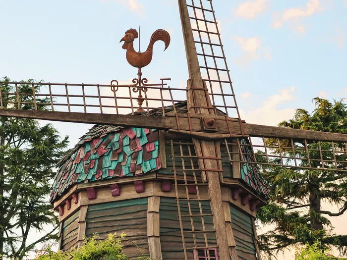 Vieux moulin à vent en bois de The Old Mill, toit à bardeaux colorés surmonté d’une girouette en forme de coq, à Fantasyland.