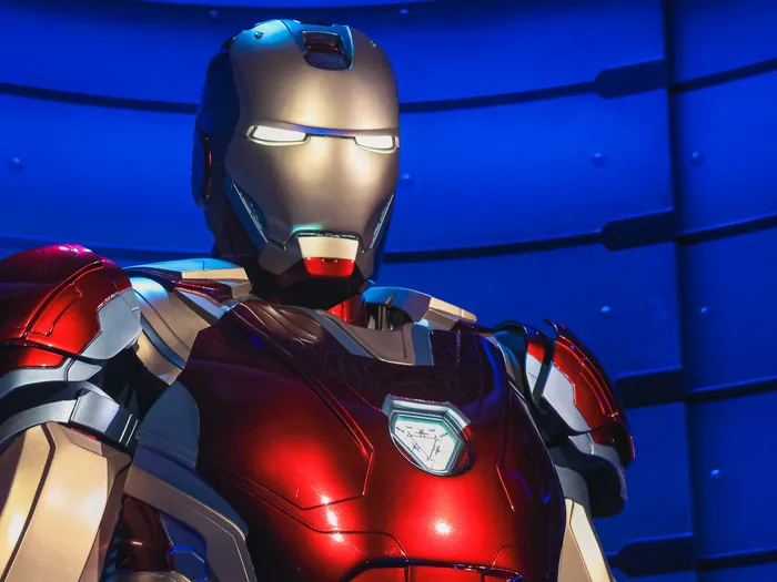 Armure rouge et argent d’Iron Man, casque éclairé, présentée devant un fond bleu à Flight Force, Avengers Campus.