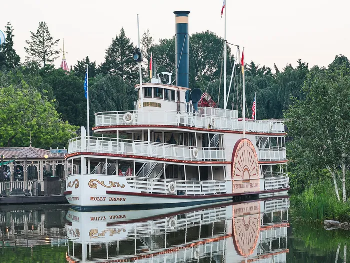 Le vapeur à roue Molly Brown amarré au ponton de Thunder Mesa Riverboat Landing, reflété dans l’eau, arbres verts en fond
