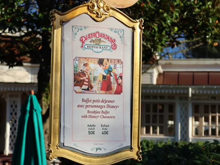 Panneau doré du Plaza Gardens annonçant le buffet petit-déjeuner avec personnages Disney, tarifs 50€ adulte et 40€ enfant.