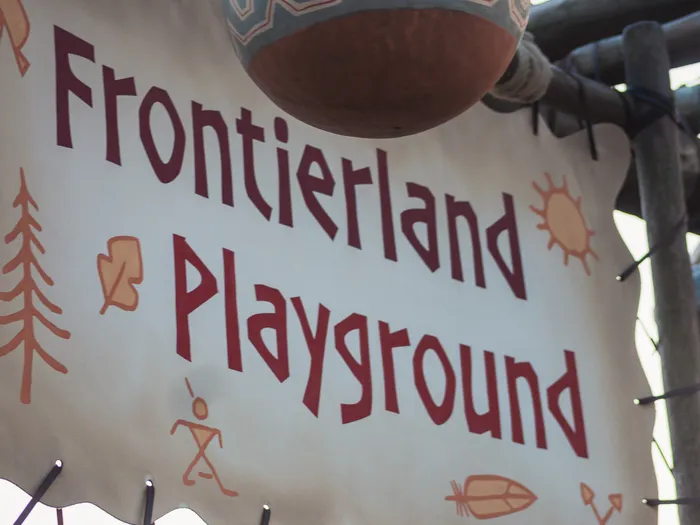 Banderole peinte « Frontierland Playground » aux motifs amérindiens à l’entrée de l’aire de jeux de Frontierland