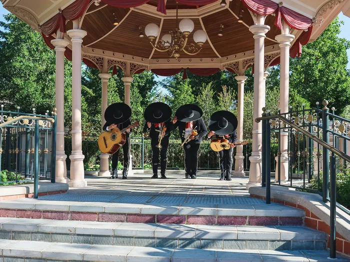 Four mariachi musicians in black sombreros play guitar and vihuela in the bandstand of the Miguel’s Fiesta Latina show at Disneyland Paris