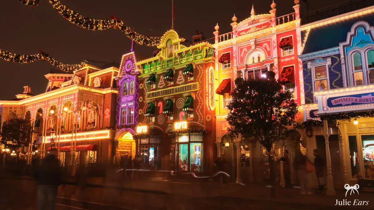 Les boutiques de Main Street USA illuminées de projections de Noël multicolores, la nuit, à Disneyland Paris