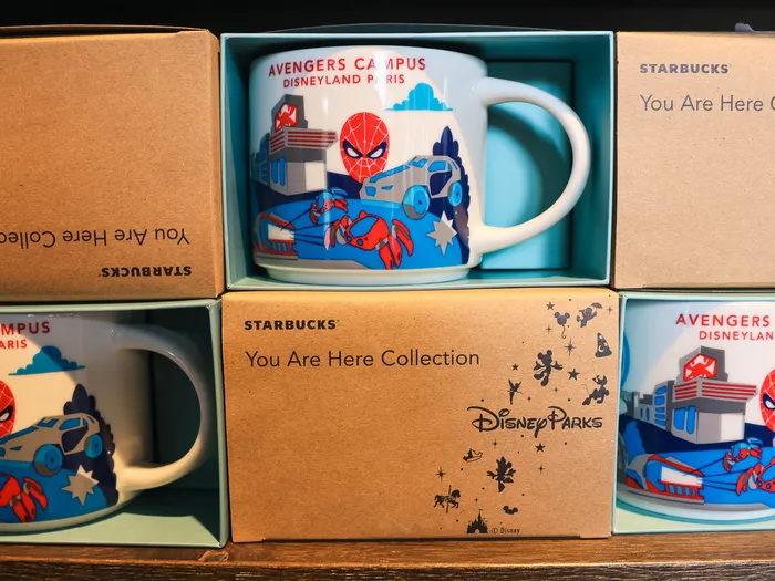 You Are Here Collection mugs from Starbucks featuring Avengers Campus Disneyland Paris and Spider-Man, lined up in their boxes on a shelf