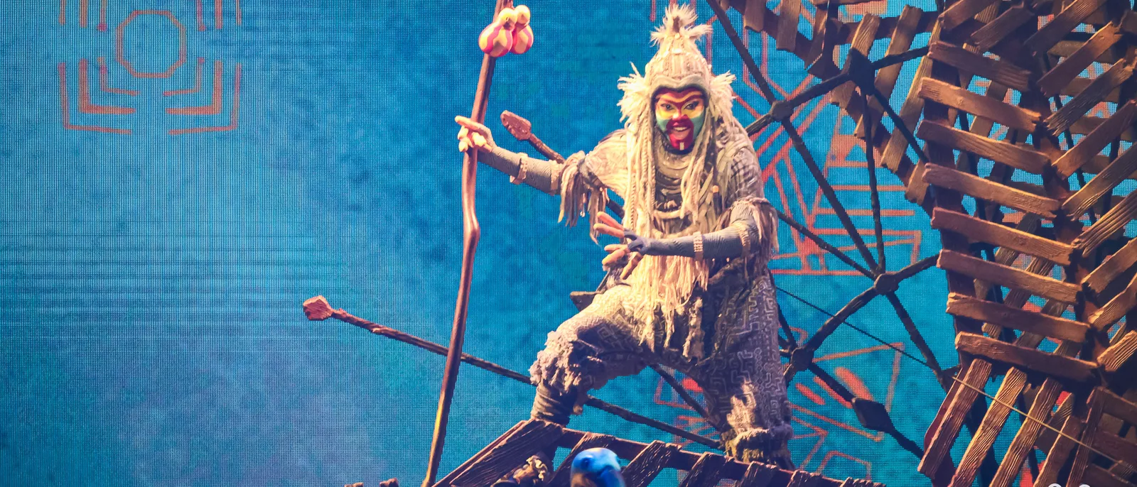 Comédien costumé en Rafiki, bâton en main, sur la scène du spectacle Mickey et le Magicien, Parc Disney Adventure World.