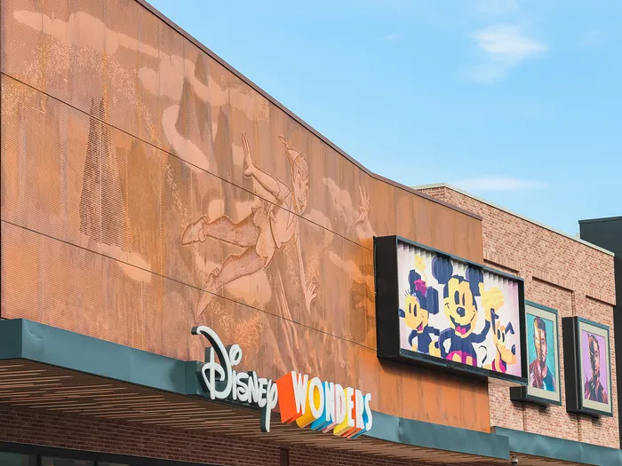 Disney Wonders shop facade at Disney Village: copper panel engraved with Peter Pan, colourful lettering and paintings of Mickey and Marvel characters