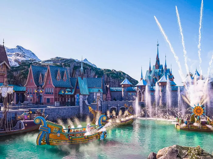 Bateaux et jets d’eau du spectacle nautique Célébration à Arendelle devant le village enneigé du land World of Frozen.