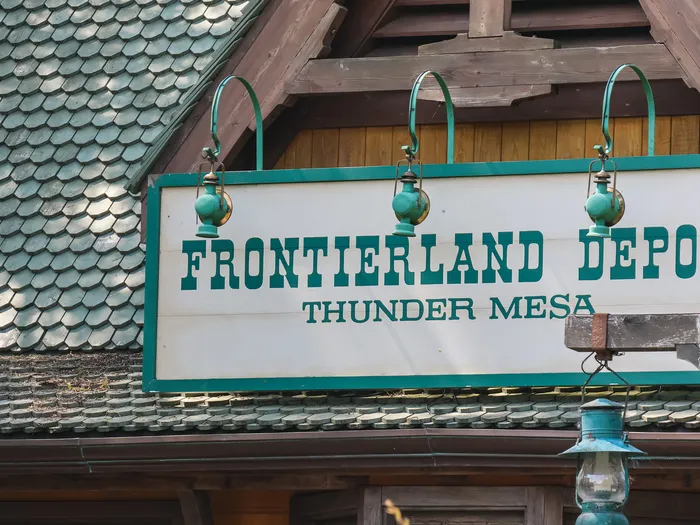 Enseigne verte « Frontierland Depot Thunder Mesa » sous le toit en bardeaux de la gare du Disneyland Railroad