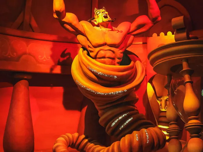 Décor éclairé de rouge montrant le Génie surgissant de sa lampe au-dessus d’Aladdin, au Passage Enchanté d’Aladdin.