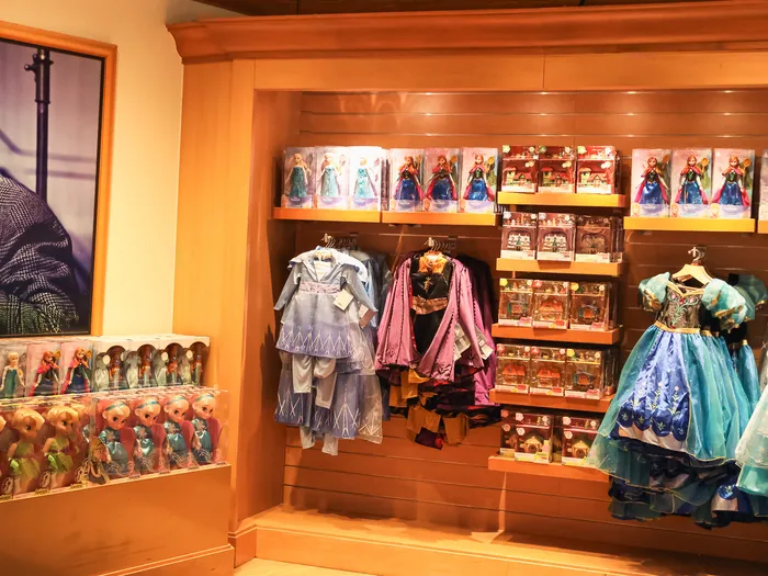 Robes et poupées La Reine des Neiges exposées près d’un portrait de Walt Disney