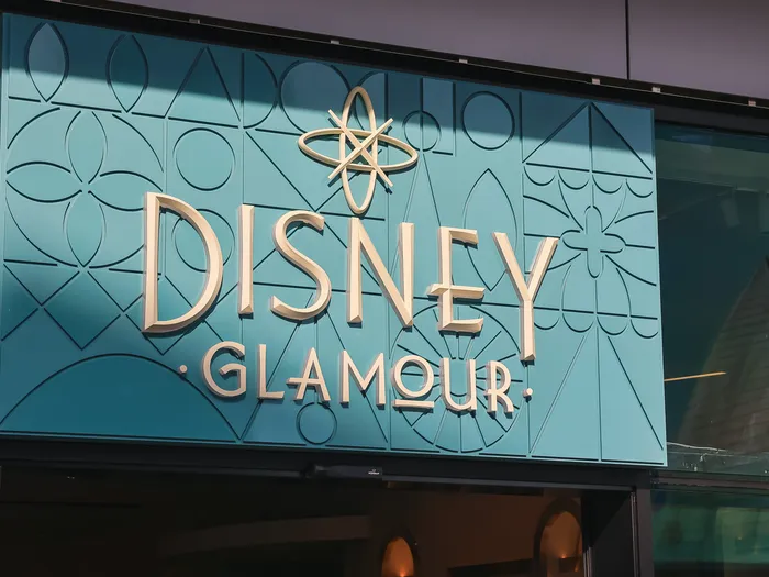 Turquoise Art Deco "Disney Glamour" sign with a gold emblem, shop at Disney Village