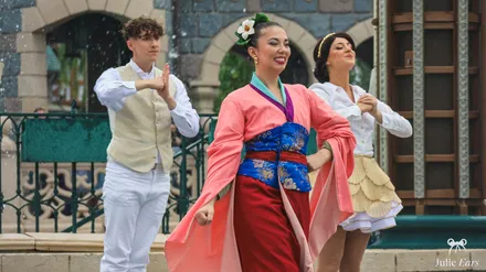 Mulan dancing in a pink outfit in front of the castle with dancers during World Princess Week at Disneyland Paris