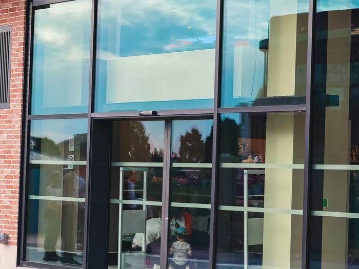Glass entrance of the Disney Wonders shop at Disney Village, with its automatic doors and brick facade.