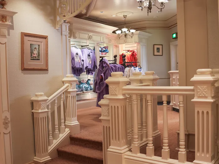 Disney Clothiers clothing shop at Disneyland Paris, with white Victorian-style staircases and balustrades and clothing rails behind