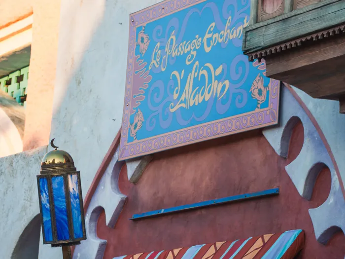 Enseigne bleue du Passage Enchanté d’Aladdin et lanterne orientale, façade d’Adventureland.