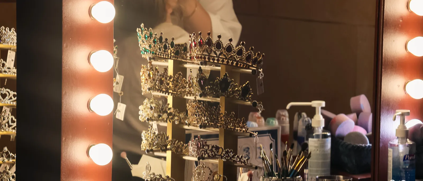 Présentoir de diadèmes devant un miroir à ampoules et des pinceaux, à un stand de maquillage de Disneyland Paris.