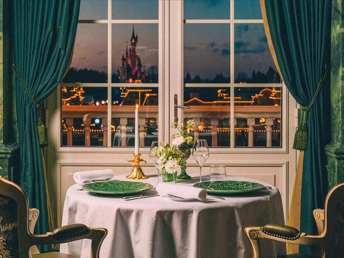 Table dressée pour deux près d’une fenêtre avec vue sur le château illuminé