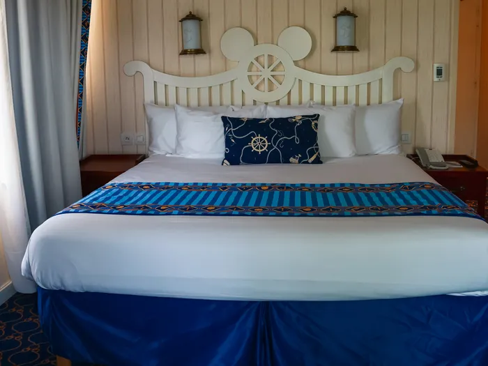 Lit double habillé de bleu marine avec tête de lit Mickey dans une chambre du Newport Bay Club