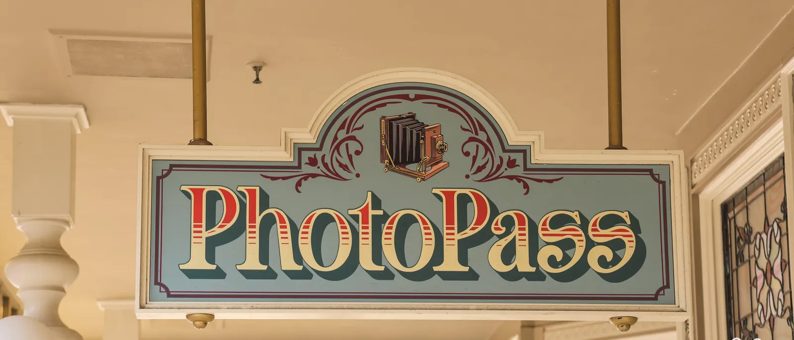 Enseigne vintage PhotoPass avec appareil photo à soufflet, suspendue sous une galerie de Main Street.