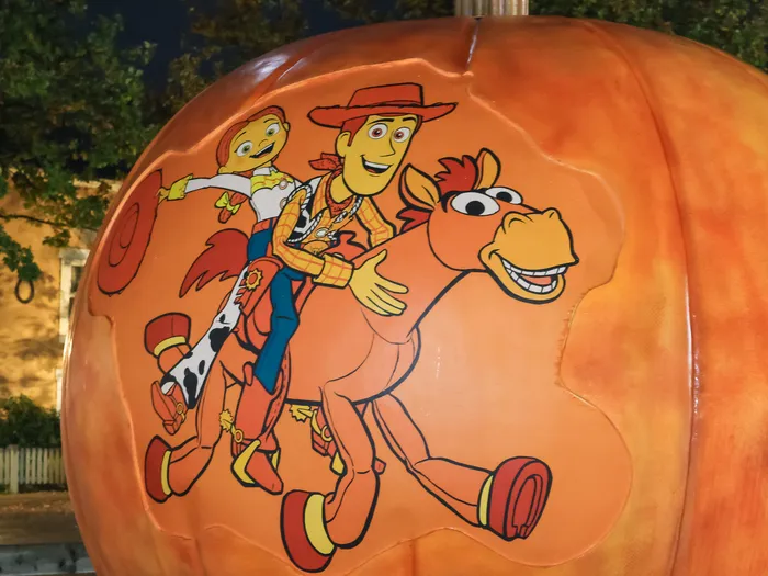 Grande citrouille décorée de Woody, Jessie et Pil-Poil illuminée la nuit près du Chuck Wagon Café