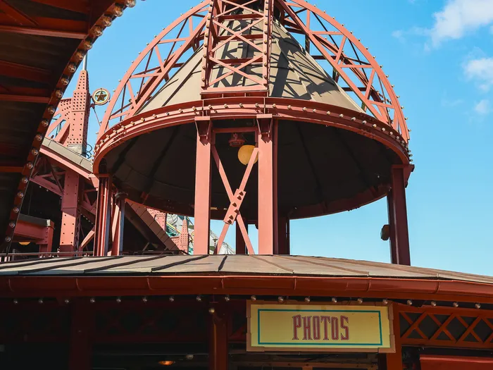 Red metal dome roof in Discoveryland style above the "Photos" sign of the Light Speed Photography shop at Disneyland Paris.