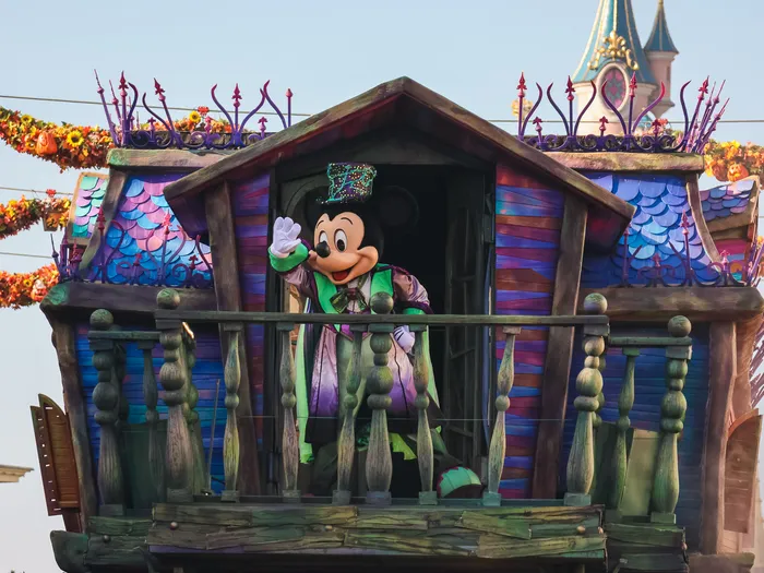 Mickey en costume salue depuis un char maison hantée sous des guirlandes de citrouilles pour Halloween à Disneyland Paris.