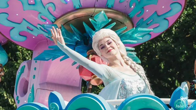 Elsa, dans sa robe bleu glacé et sa couronne de glace, salue lors de la parade La Reine des Neiges à Disneyland Paris.