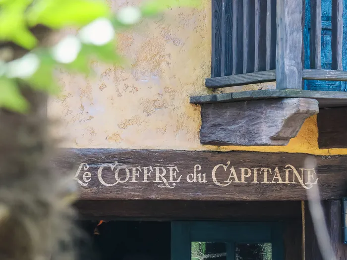 Outside facade with the painted Le Coffre du Capitaine sign and a blue wooden balcony at Disneyland Paris