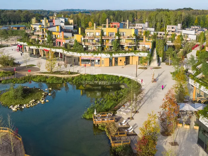 Vue aérienne des Villages Nature Paris avec hébergements végétalisés bordant un lac