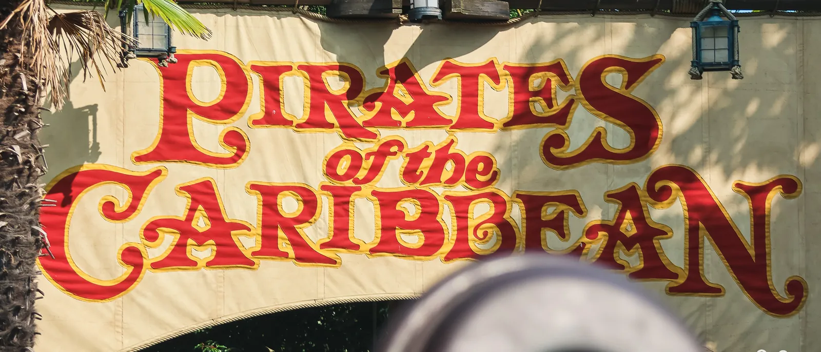 L’enseigne rouge Pirates of the Caribbean au-dessus d’un canon à l’entrée de l’attraction, à Adventureland.