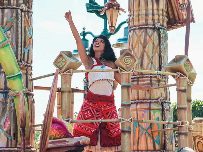 Vaiana, bras levés, sur son char lors de la Cavalcade des Princesses à Disney Adventure World