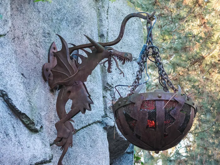 Applique en fer forgé en forme de dragon tenant une lanterne rougeoyante à l’entrée de La Tanière du Dragon.