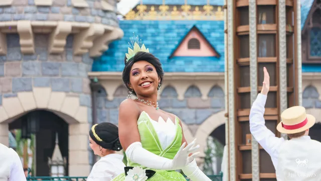 La princesse Tiana, robe verte et diadème, sourit lors de la parade devant le château à Disneyland Paris.
