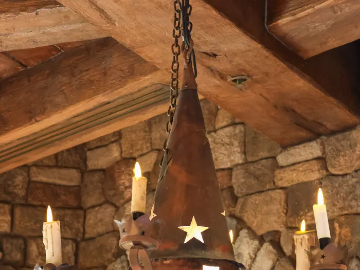 Wrought-iron chandelier shaped like a starry wizard’s hat, topped with candles, under the beams of the Merlin l’Enchanteur shop at Disneyland Paris.