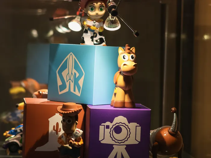 Lit display case of Toy Story figures at the Animation Boutique at Disneyland Paris: Jessie, Bullseye and Woody standing on colourful boxes.