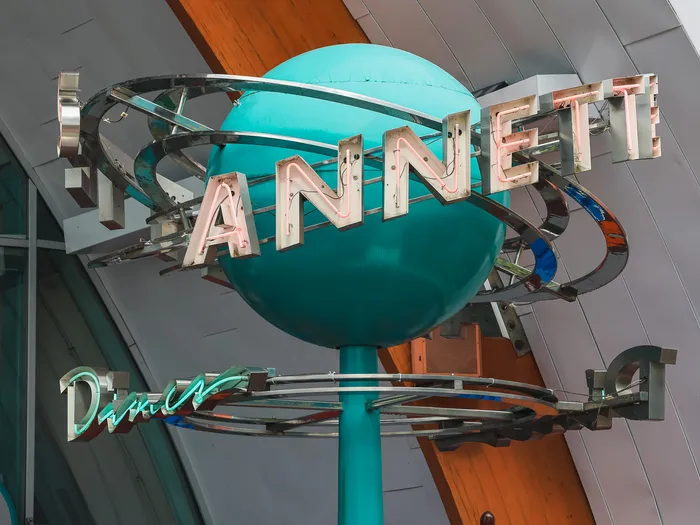 Enseigne rétro en forme de globe turquoise entouré d’anneaux, avec les lettres Annett’s du restaurant.