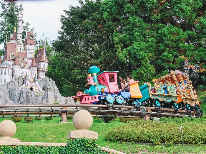 Train du cirque Casey Jr. aux wagons colorés glissant devant le château de la Bête, à Fantasyland.