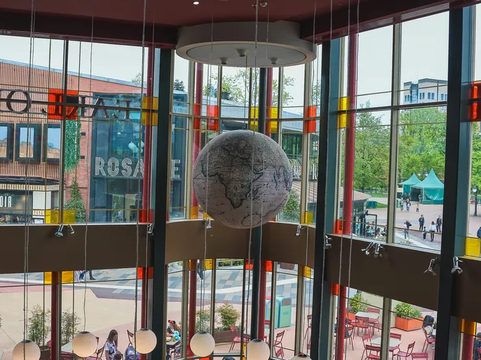 Salle lumineuse du Earl of Sandwich avec globe suspendu et grandes baies donnant sur Disney Village