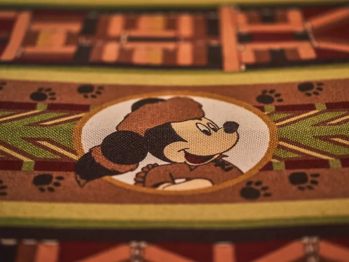 Détail d’un tissu décoratif figurant Mickey en trappeur et des empreintes de pattes, au Crockett’s Saloon du Davy Crockett Ranch