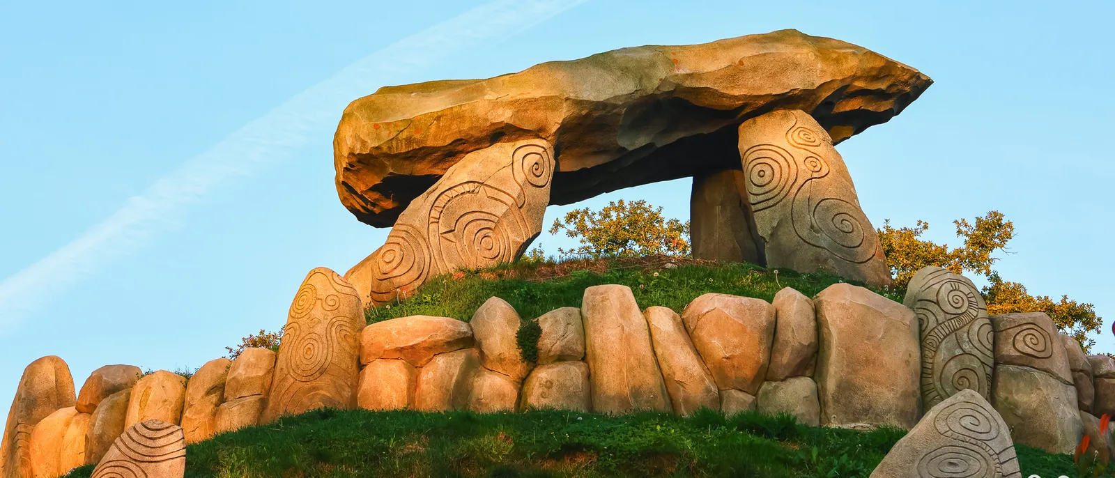Dolmen géant posé sur une butte herbeuse à l’entrée de Goudurix, pierres gravées de spirales dans la lumière du soir